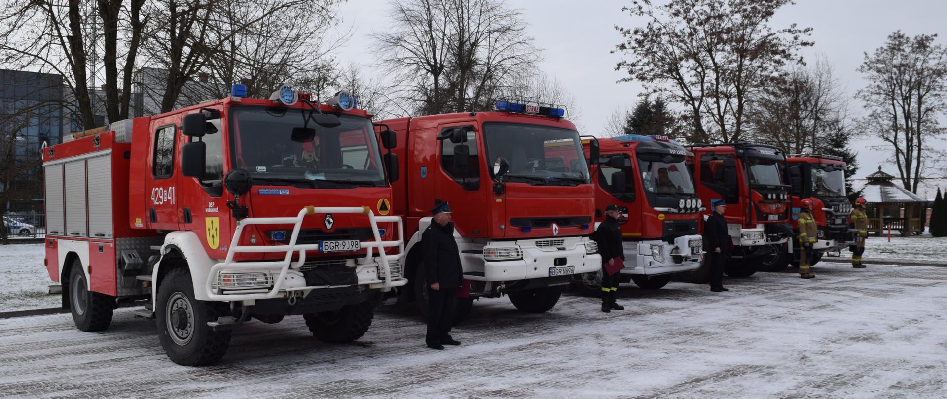 Pojazdy strażackie stoją na placu.