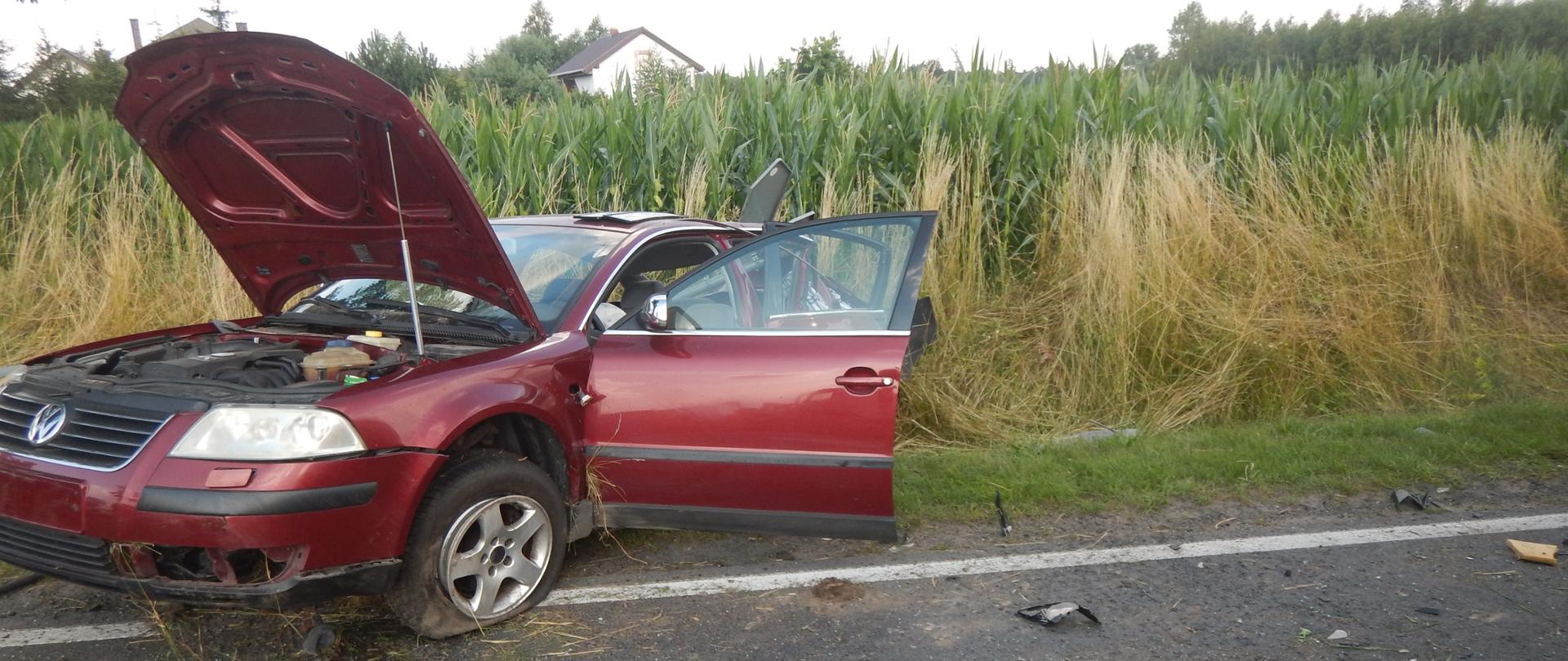 Zdjęcie przedstawia czerwony samochód osobowy marki VW, który brał udział w zdarzeniu. Samochód znajduje się częściowo w rowie.