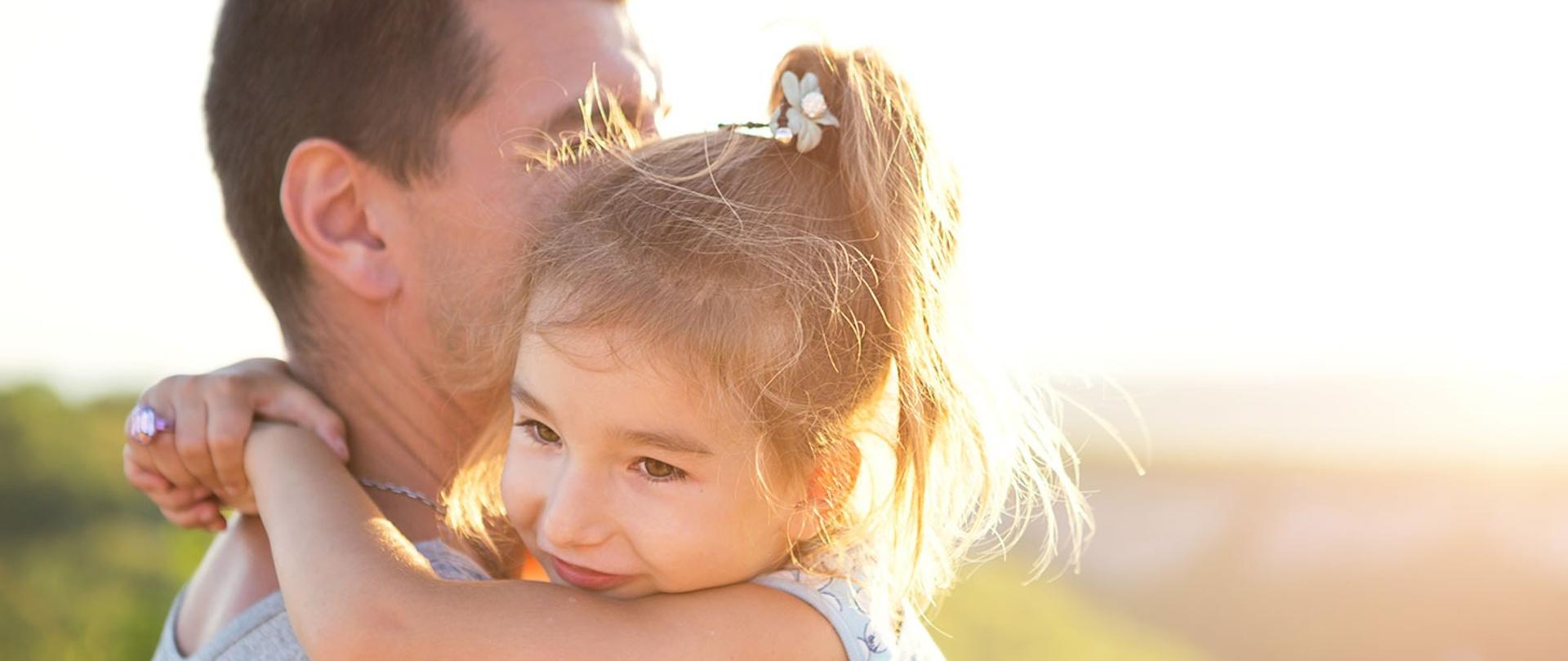 Zdjecie ojca tulacego swoja córkę w słoneczny dzień