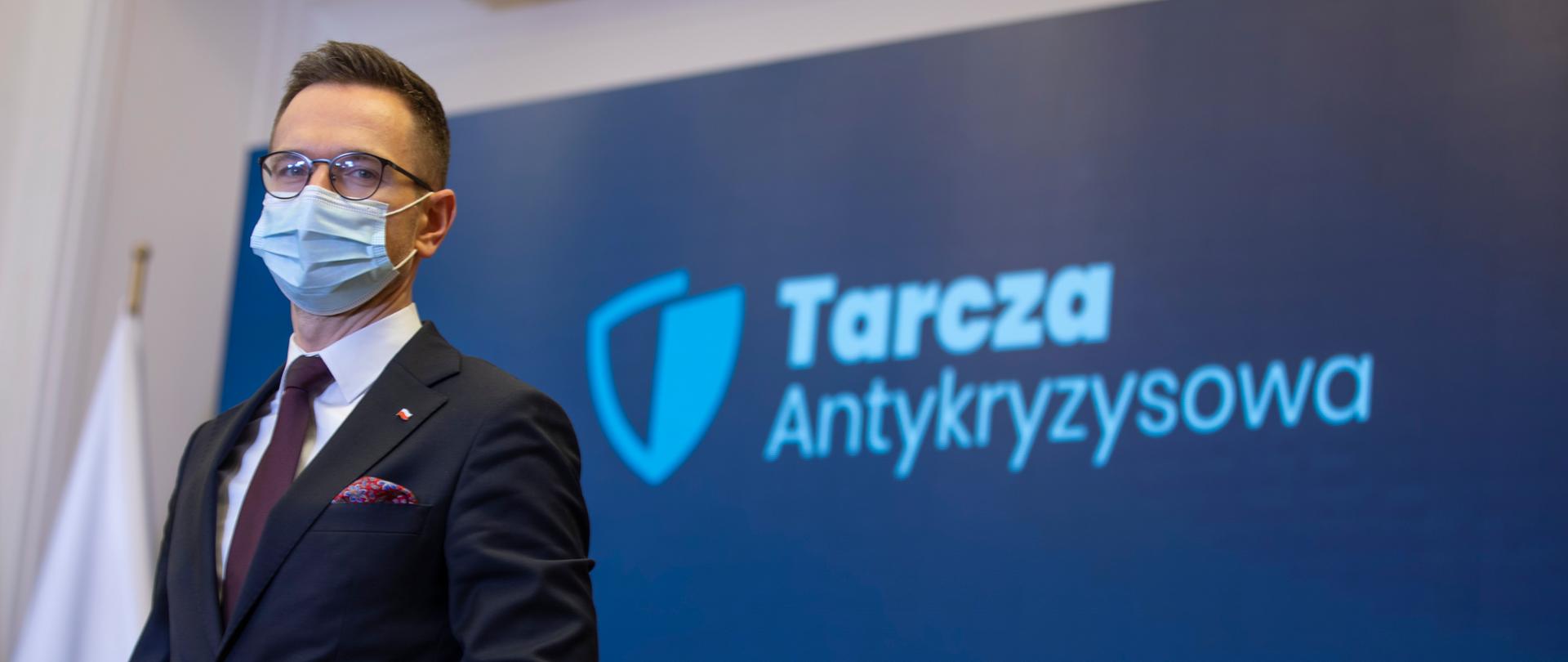 Minister Buda na tle napisu "Tarcza Antykryzysowa"