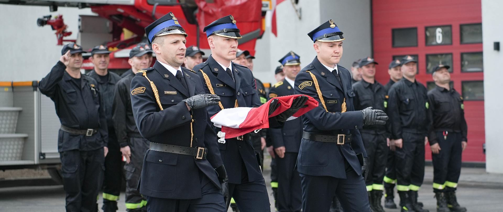 Poczet flagowy maszeruje do podniesienia flagi na tle jednostki