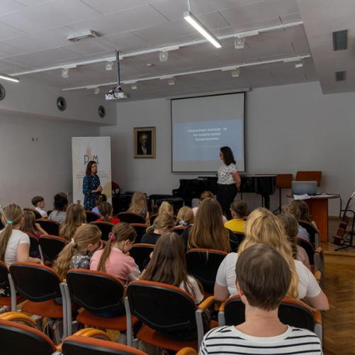 Koncert i warsztaty kompozytorskie 2024. Pani Agnieszka Niesler prowadząca warsztaty kompozytorskie. Uczniowie zgromadzeni na warsztatach w auli PSM w w Głubczycach.