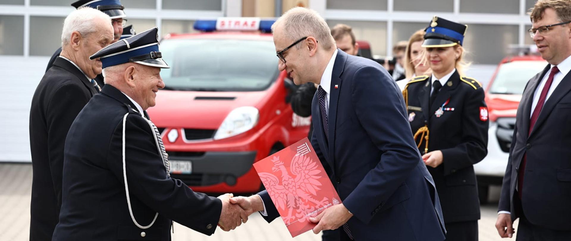 Na zdjęciu widać wiceministra Błażeja Poożego wręczającego decyzję o przyznaniu świadczenia emerytalnego. 