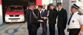 Gorzyce - przekazanie samochodu - Przedstawiciele jednostki OSP Gorzyce wręczają podziękowania zaproszonym gościom. W tle widać strażnice i samochód. 