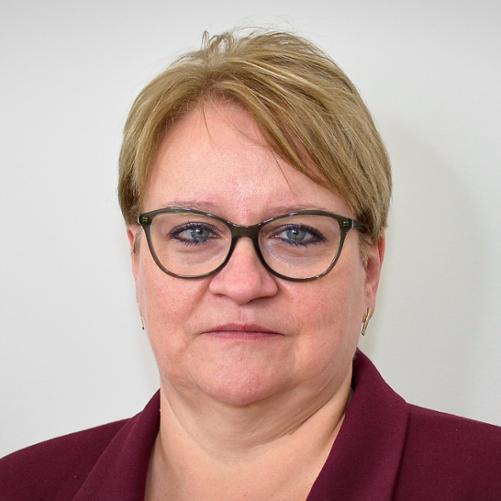 Kobieta w bordowej marynarce, w okularach, z krótkimi włosami