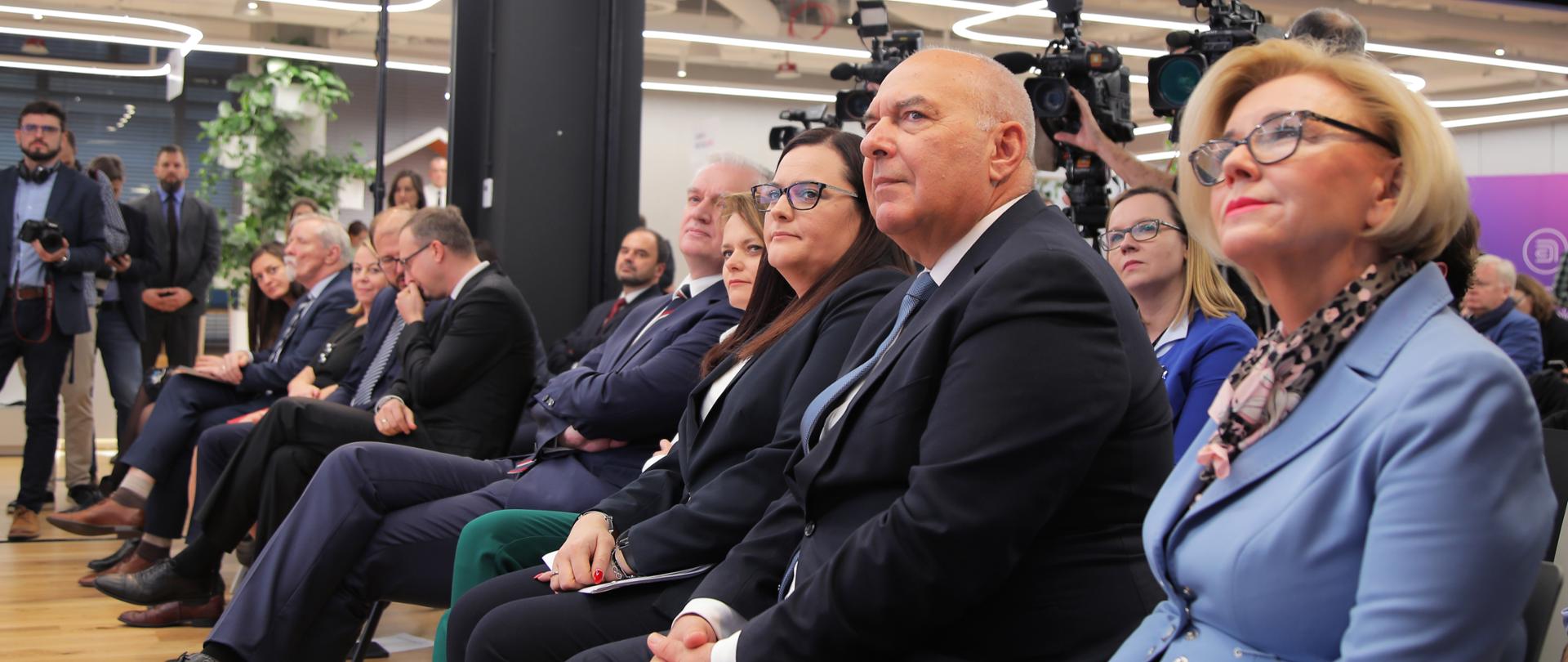 Podczas konferencji uczestnicy siedzą na krzesłach ustawionych w rzędach. W pierwszym szeregu od lewej Jarosław Gowin, Jadwiga Emilewicz, Małgorzata Jarosińska-Jedynak oraz Tadeusz Kościński.