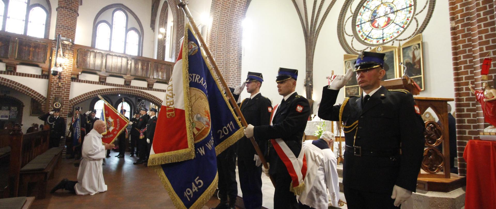 Zdjęcie przedstawia poczet sztandarowy ze sztandarem KP PSP w Wałczu oddający honory w trakcie mszy świętej z okazji Dnia Strażaka w kościele pw. Św. Antoniego w Wałczu 