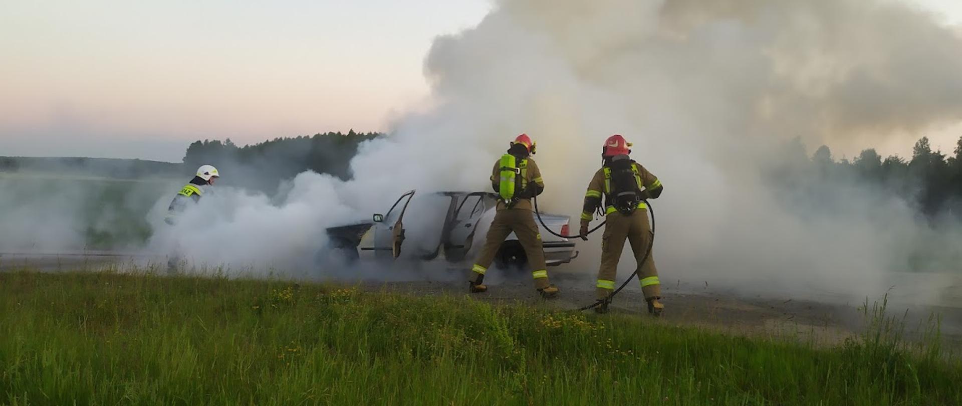 Zdjęcie przedstawia strażaków podczas akcji gaszenia samochodu osobowego 