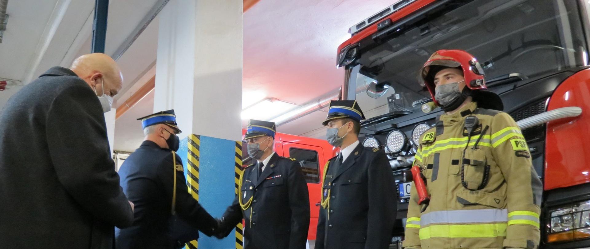 Zdjęcie przedstawia moment przekazania nowy ciężki samochód ratowniczo-gaśniczy SCANIA w pomieszczeniu garażowym. st.bryg. Robert Wiśniewski – Zastępca Kujawsko-Pomorskiego Komendanta Wojewódzkiego Państwowej Straży Pożarnej przekazuje pojazd na ręce st.bryg. Waldemara Szrull - Komendanta Powiatowego PSP w Brodnicy.