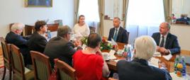 Zdjęcie w poziomie. Uczestnicy spotkania siedzą przy stole. Członkowie KRRiT siedzą naprzeciwko Prezydenta. Członkowie widoczni są od tyłu.