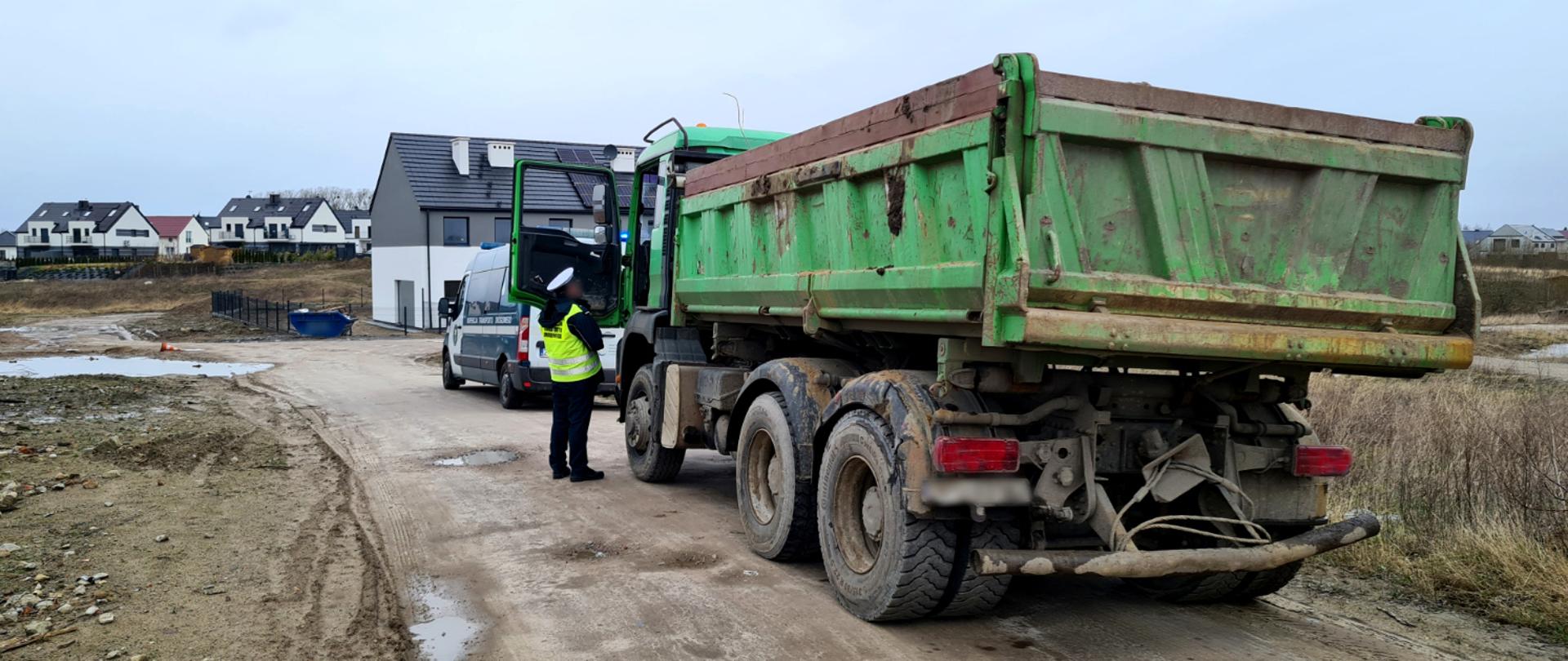 Wywrotka zatrzymana przez inspektorów zachodniopomorskiej Inspekcji Transportu Drogowego. Na pierwszym planie ciężarówka, z której kierowcą rozmawia inspektor ITD. Przed nią inspekcyjny furgon. W tle zabudowania mieszkalne.