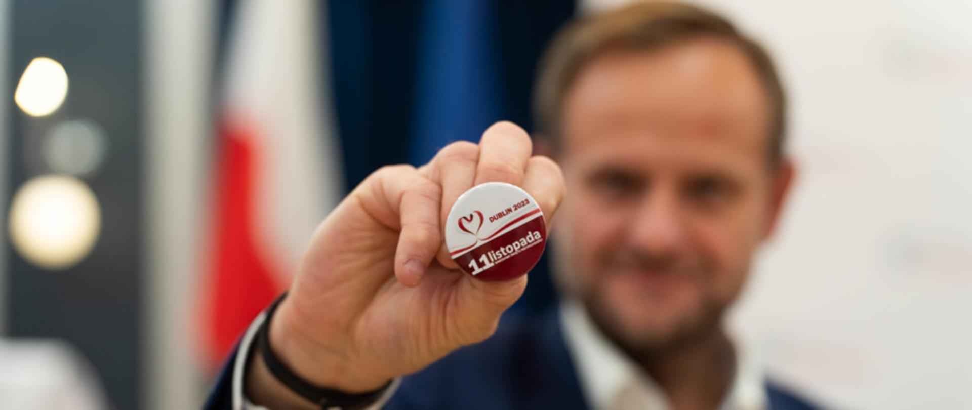 Jacek Jaszczyk prezentuje przypinkę okolicznościową