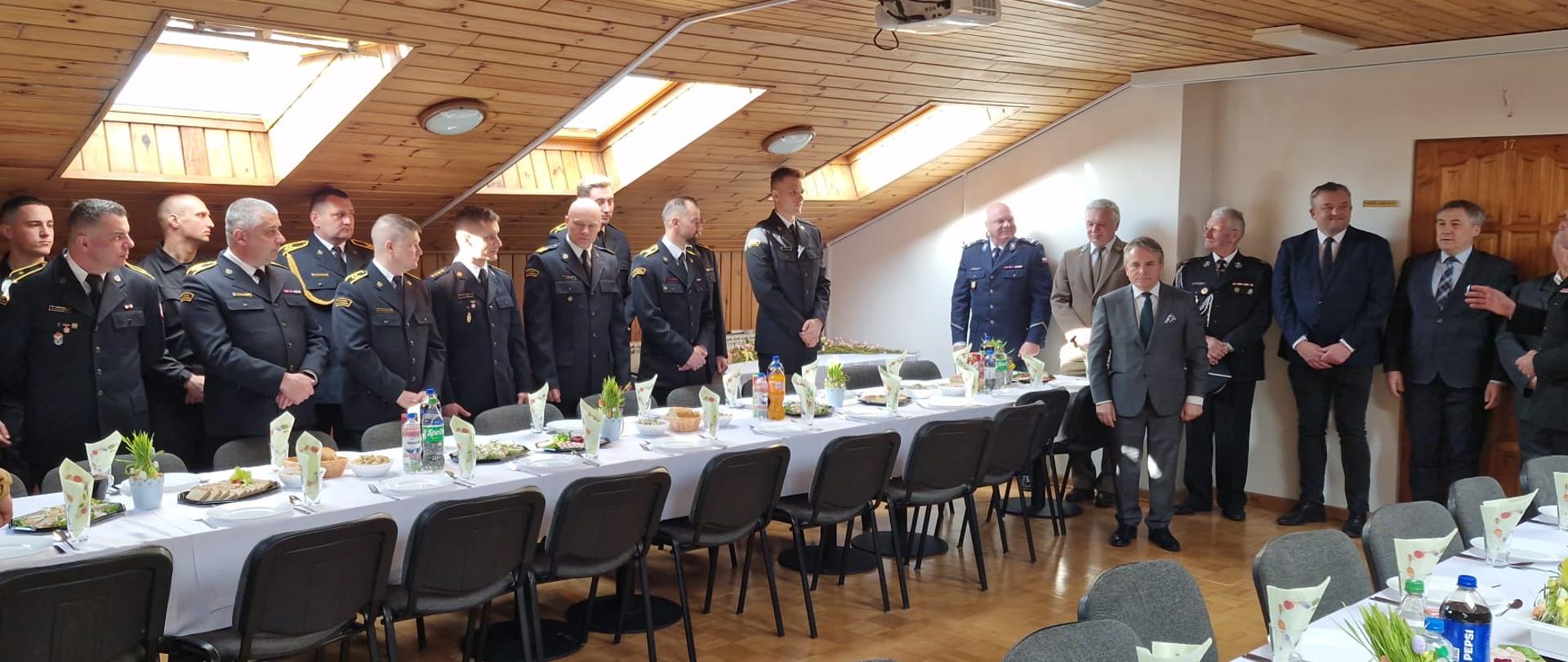 Zdjęcie przedstawia grupę strażaków w mundurach służbowych podczas spotkania wielkanocnego.