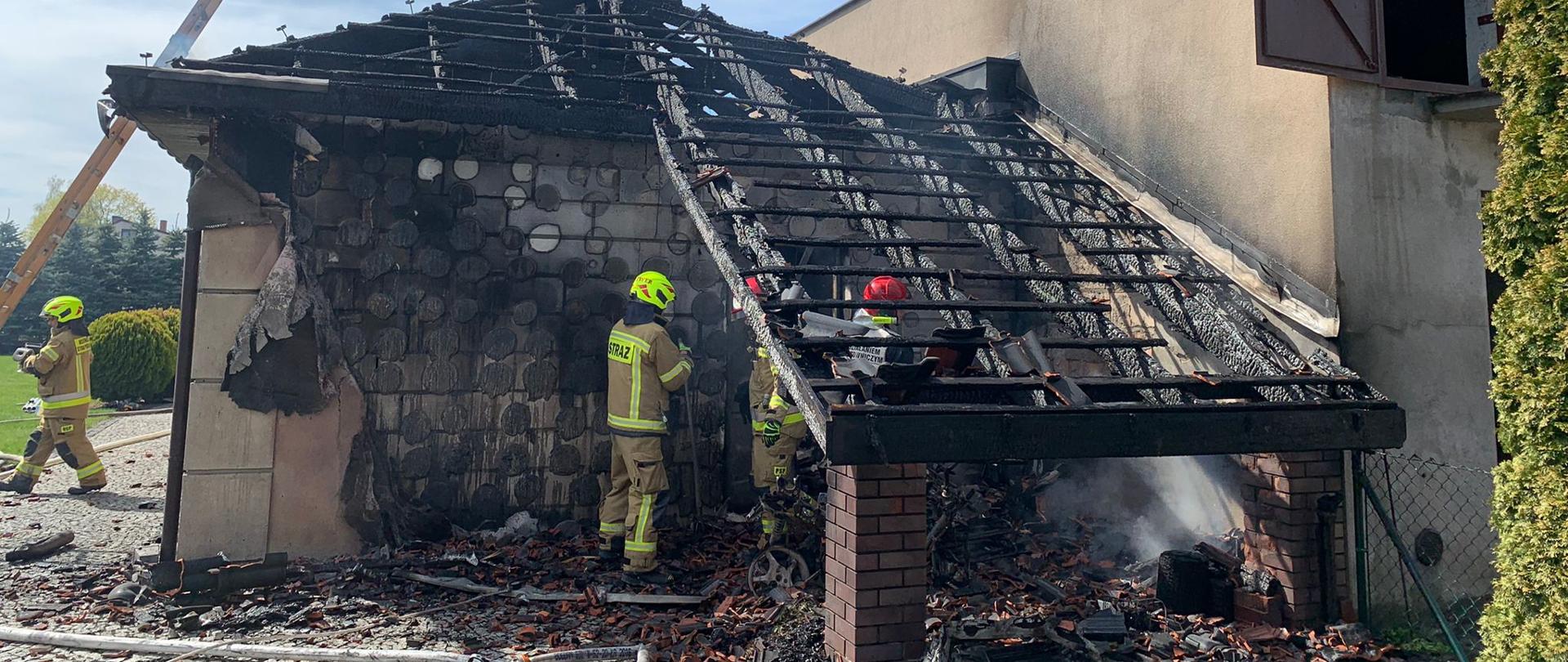 Spalona konstrukcja dachu, strażacy prowadzący prace rozbiórkowe.