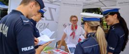 Pracownik ZER MSWiA udziela informacji wskazówek funkcjonariuszom policji przeglądającym broszury informacyjne