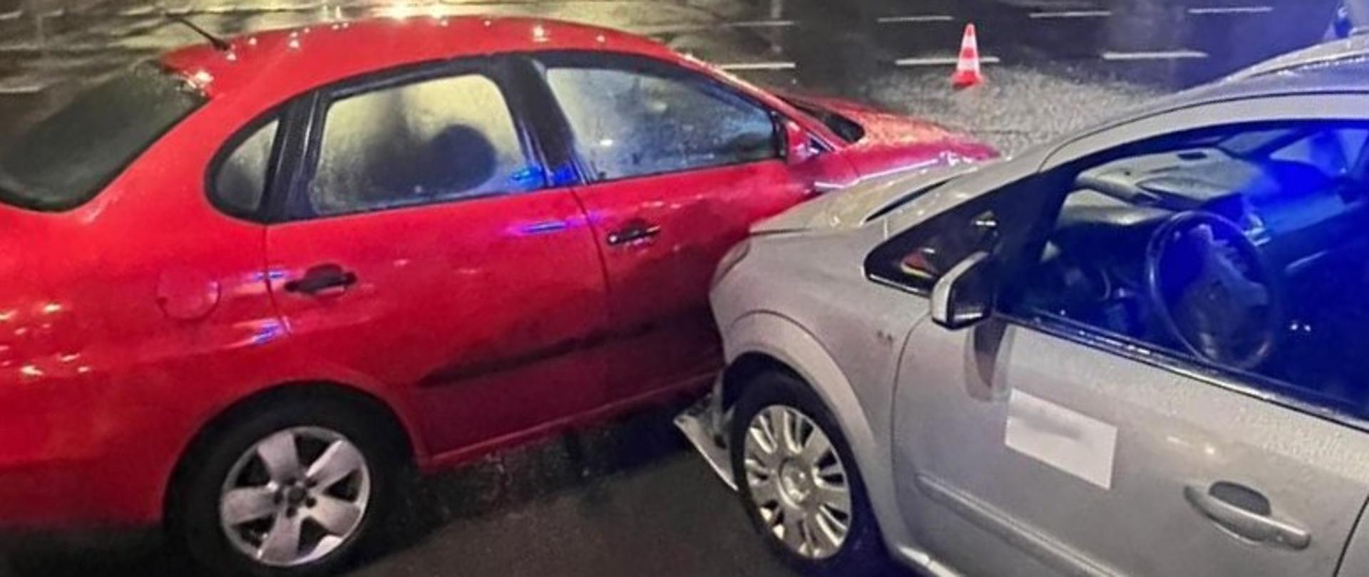 Zdjęcie przedstawia skrzyżowanie na którym zderzyły się dwa auta osobowe. Po lewej stronie stoi czerwony Seat a po prawej stronie widać Opla Zafirę.