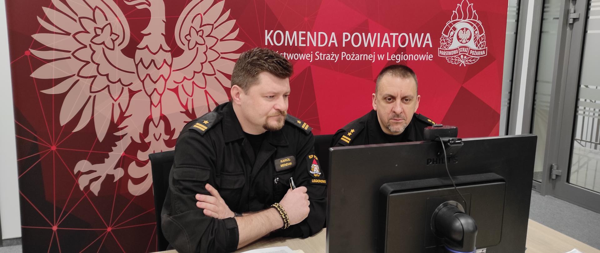 Wideokonferencja w sprawie dodatku ratowniczego dla druhów OSP. Na zdjęciu przed monitorem 2 strażaków w mundurach sztabowych. Z lewej Z-ca Komendanta Powiatowego PSP w Legionowie mł. bryg. Karol Mendak po prawej Naczelnik wydziału op[eracyjnego bryg. Tomasz Wołoszyn.