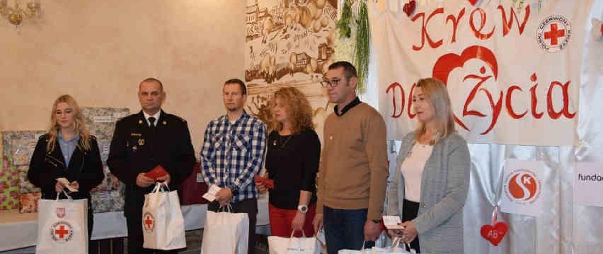 Zdjęcie zrobione w pomieszczeniu. Na zdjęciu widać sześć osób, które otrzymują wyróżnienia . 