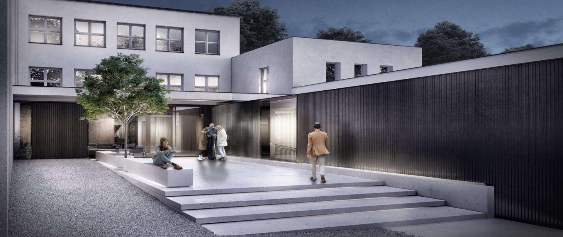 Zdjęcie przedstawia widok dwupiętrowego, białego budynku szkoły znajdującego się za wyłożonymi granitowymi płytami schodami. Z przodu budynku znajduje się przeszkolone wejście, przed którym stoi grupka uczniów i rodziców.