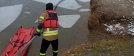 Na zdjęciu strażacy ćwiczą na zalodzonym zbiorniku wodnym