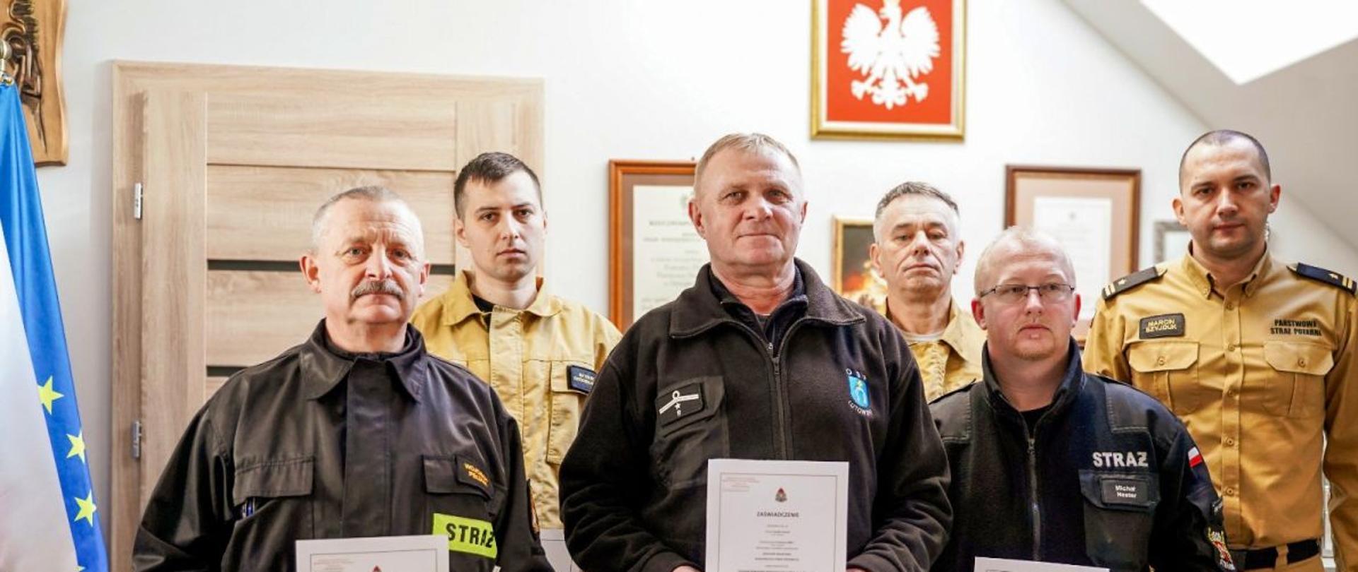 Zdjęcie wykonane w biurze komendanta. Przedstawia zastępcę komendanta oraz strażaków OSP którzy ukończyli kurs naczelników OSP. 