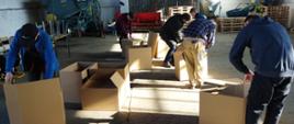 Pracownicy techniczni przygotowują pudełka kartonowe w Powiatowym Magazynie Pomocy