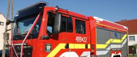 Na zdjęciu znajduje się samochód pożarniczy, w tle widać budynki