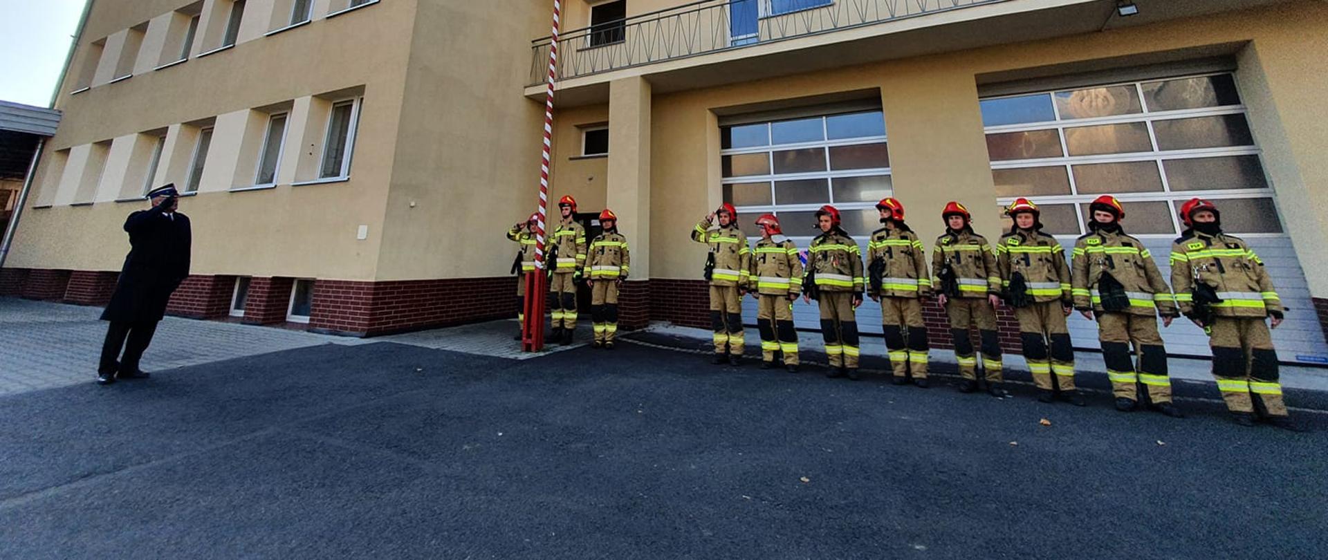 Strażacy śpiewający Hymn Polski i wciągający Flagę na maszt.