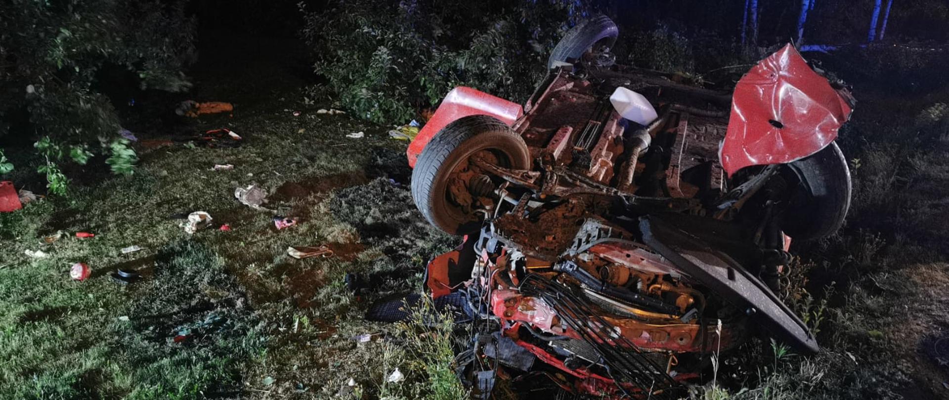 Widoczne miejsce zdarzenia uszkodzony pojazd oraz strażacy działający na miejscu zdarzenia.