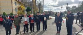 Druhowie stoją na placu przed strażnicą. Poseł Aleksander Mrówczyński i Pomorski Komendant Wojewódzki dokonują wręczenia świadczeń ratowniczych.
