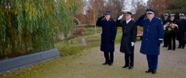 Przedstawiciele służb mundurowych Ministerstwa Spraw Wewnętrznych i Administracji oddają honory. Za nimi stoją żołnierze z kwiatami.