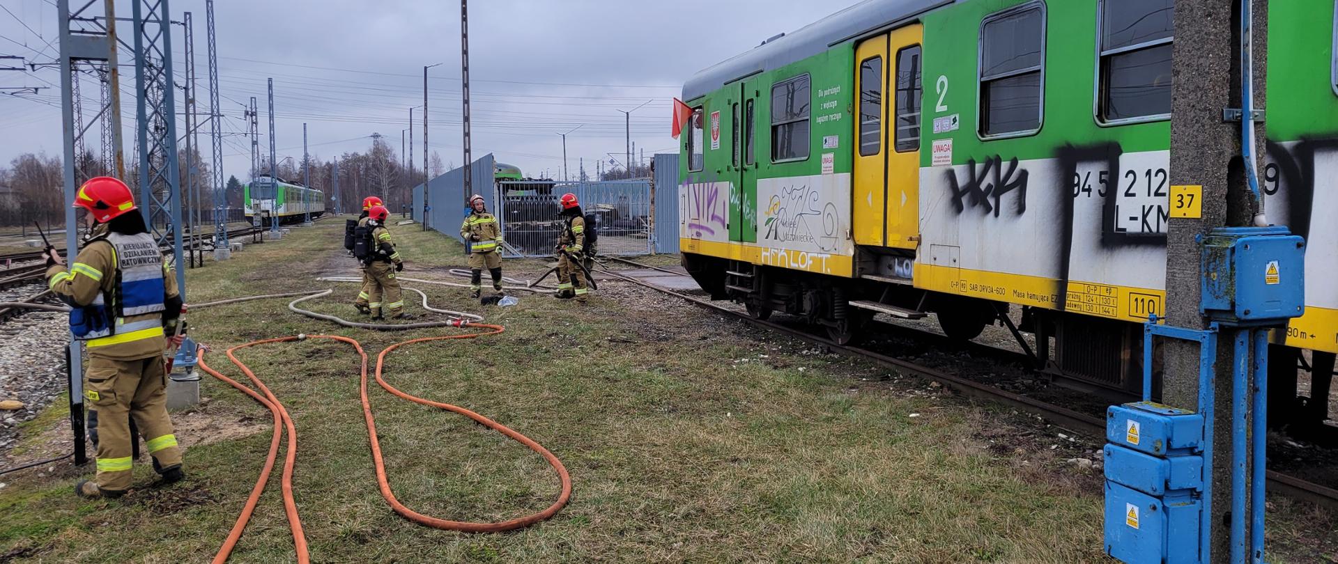 Zdjęcia przedstawiają działania strażaków podczas pożaru pociągu elektrycznego. Strażacy prowadzą działania na bocznicy kolejowej na terenie Sekcji Napraw i Eksploatacji Taboru Kolejowego w Tłuszczu. 