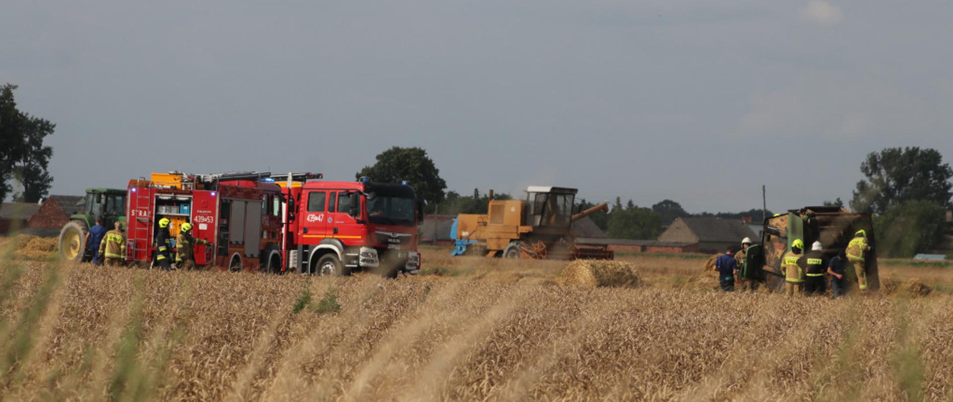 Na zdjęciu dwa samochody pożarnicze, kombajn oraz prasa. 