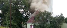 Widać ciemny dym palącego się budynku gospodarczego połączonego z mieszkalnym.