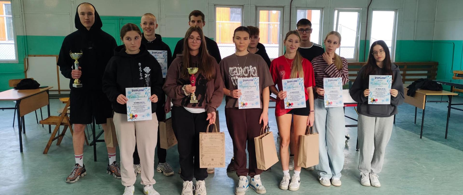 Uczniowie i uczennice z dyplomami, pucharami i nagrodami 