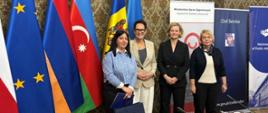Stoją od lewej: jedna z uczestniczek programu, szefowa służby cywilnej Anita Noskowska-Piątkowska, zastępczyni dyrektora Departamentu Współpracy Rozwojowej MSZ Zuzanna Kierzkowska, dyrektor KSAP Małgorzata Bywanis-Jodlińska; w tle flagi państw uczestniczących w programie