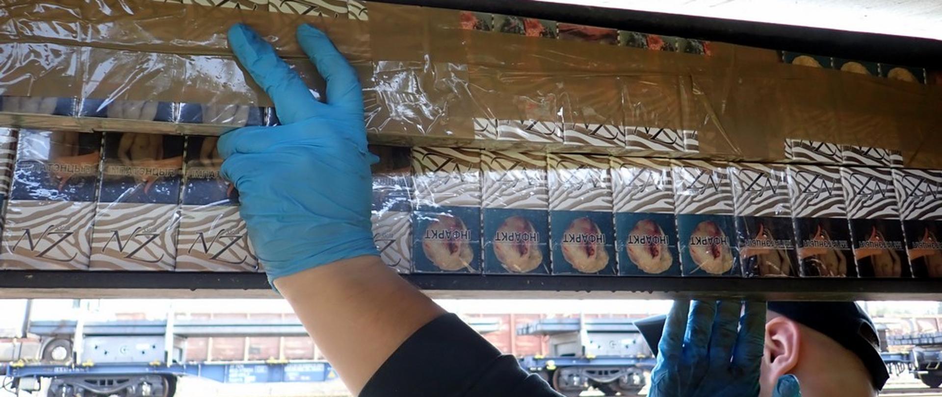 Funkcjonariusz wyjmuje papierosy z podwozia wagonu