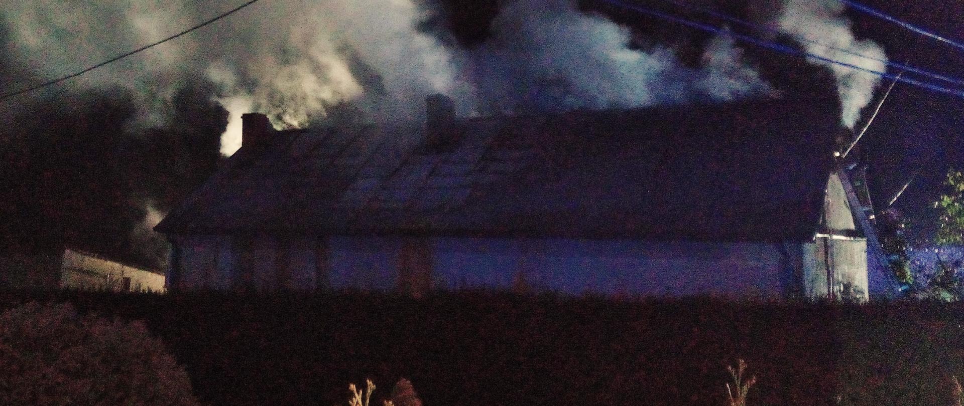 Zdjęcie przedstawia budynek mieszkalny gdzie wybuchł pożar. Widać dym i parę wodną unoszącą się nad dachem.