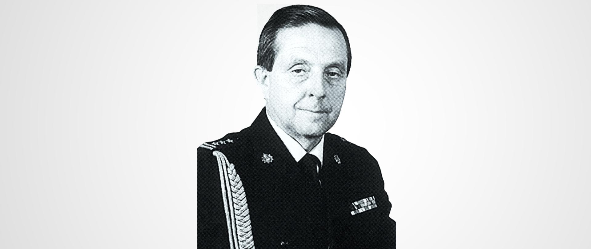 Zdjęcie portretowe oficera Państwowej Straży Pożarnej w stopniu starszego brygadiera w mundurze wyjściowym.