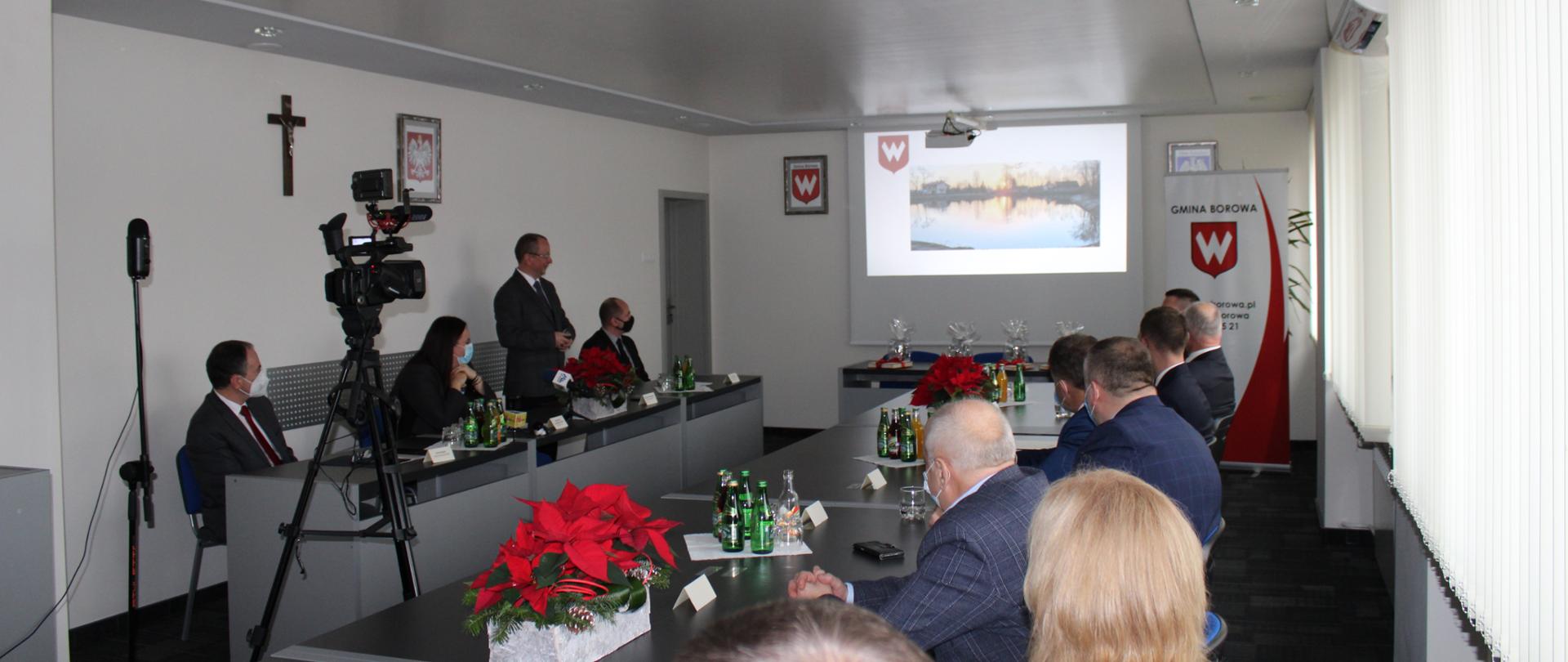 Uczestnicy konferencji prezentującej inwestycje w gminie Borowa, na ekranie zdjęcie zbiornika retencyjnego Sicina.