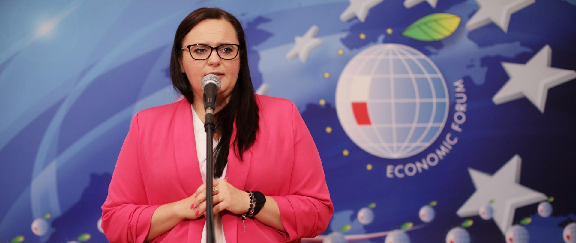 Minister Jarosińska-Jedynak mówi do mikrofonu, za nią jest ścianka promocyjna Economic Forum