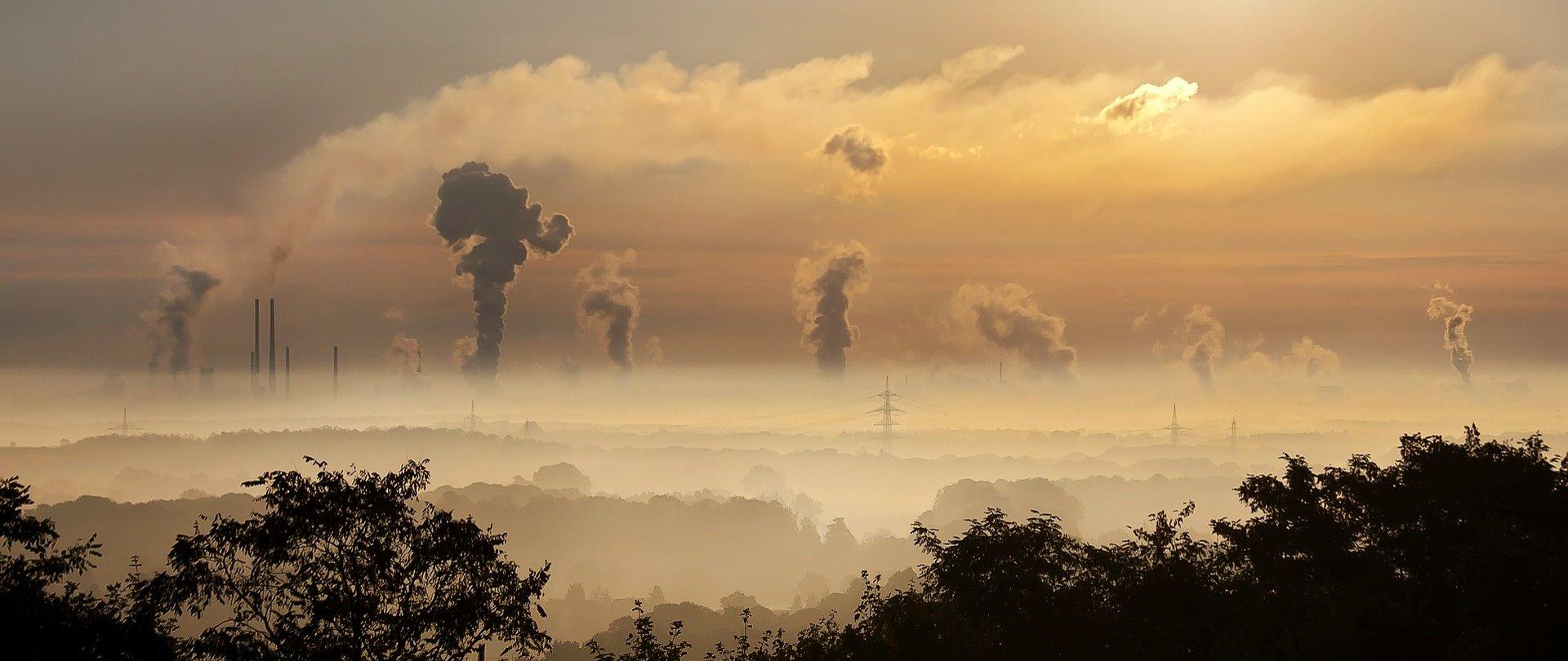 Zdjęcie przedstawia dymiące kominy i nieprzejrzyste powietrze z powowdu smogu