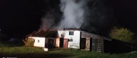 Pora nocna, na zdjęciu widać stojący budynek obory z którego wnętrza unosi się dym. Dach budynku doszczętnie spalony, widoczny tylko stelaż.