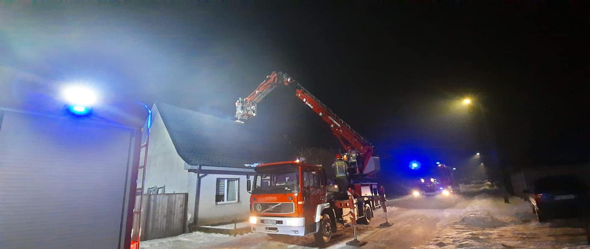 strażacy w koszu podnośnika przy pożarze komina 