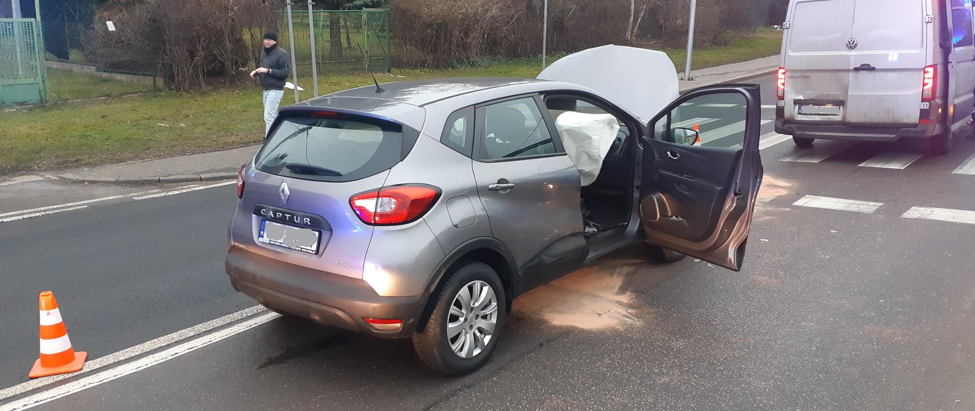 Samochód osobowy Renault z podniesioną maską po kolizji z busem Policji do przewozu osadzonych.