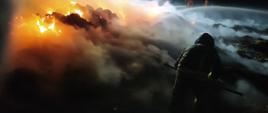 Na zdjęciu strażak podczas gaszenia słomy