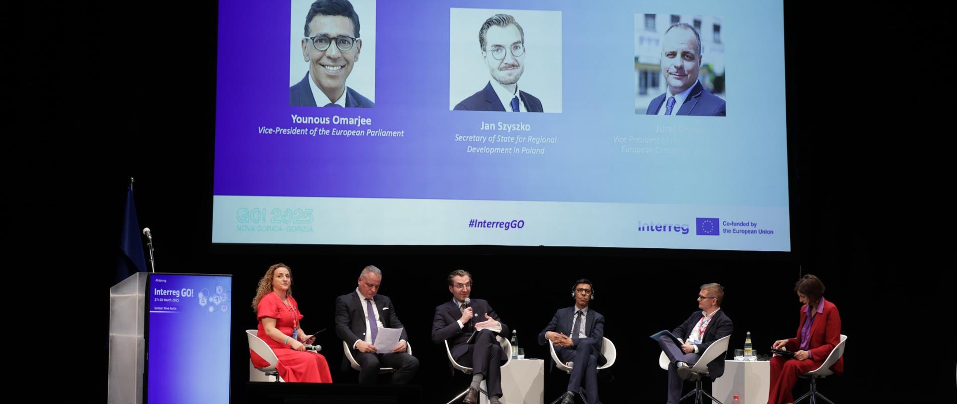 Grupa osób siedzi w fotelach na scenie i rozmawia w czasie panelu