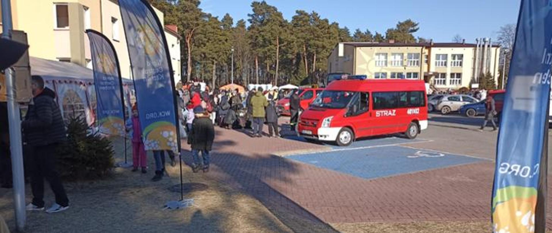 na zdjęciu budynki grupa osób oraz strażacki mikrobus