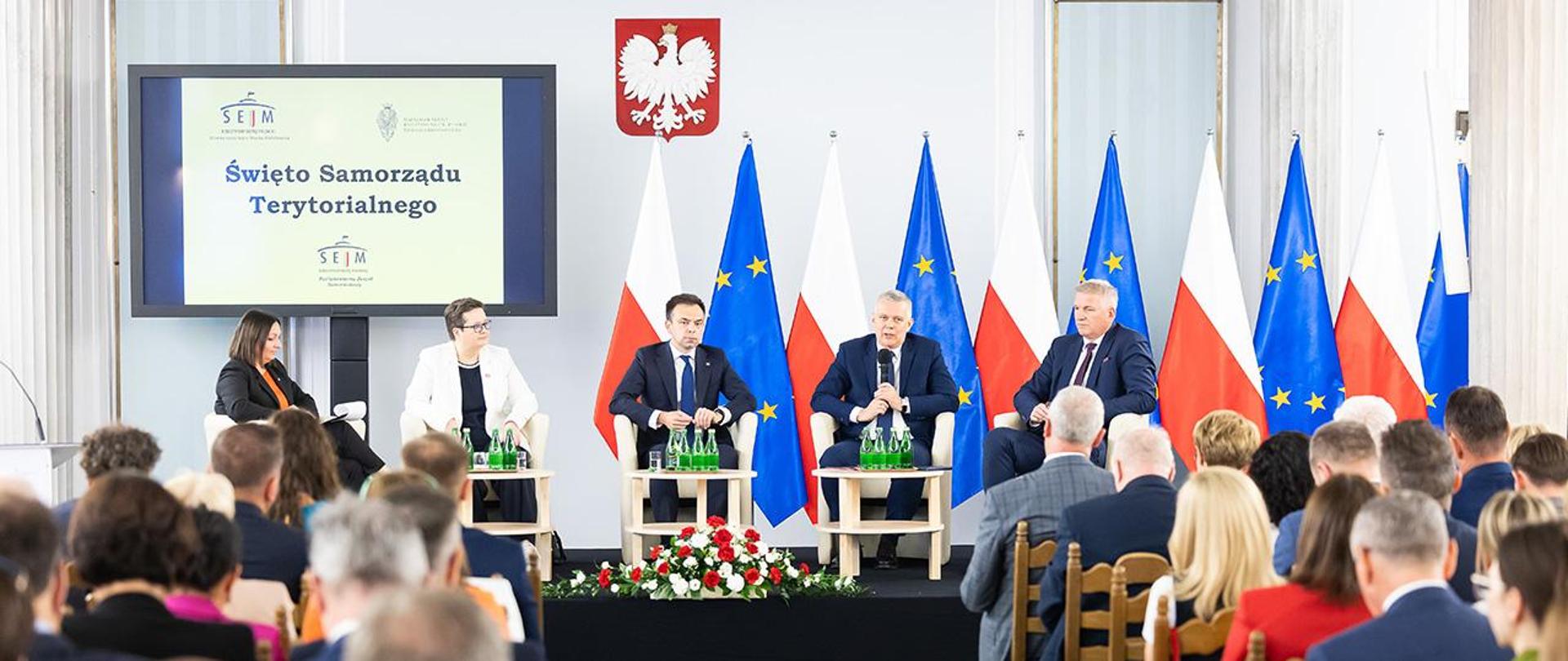 Na zdjęciu widać prelegentów bloku konferencji, m. in. ministra Tomasza Siemoniaka i innych uczestników konferencji. 
