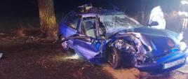 Rozbity samochód osobowy Honda Civic koloru niebieskiego po uderzeniu w drzewo.